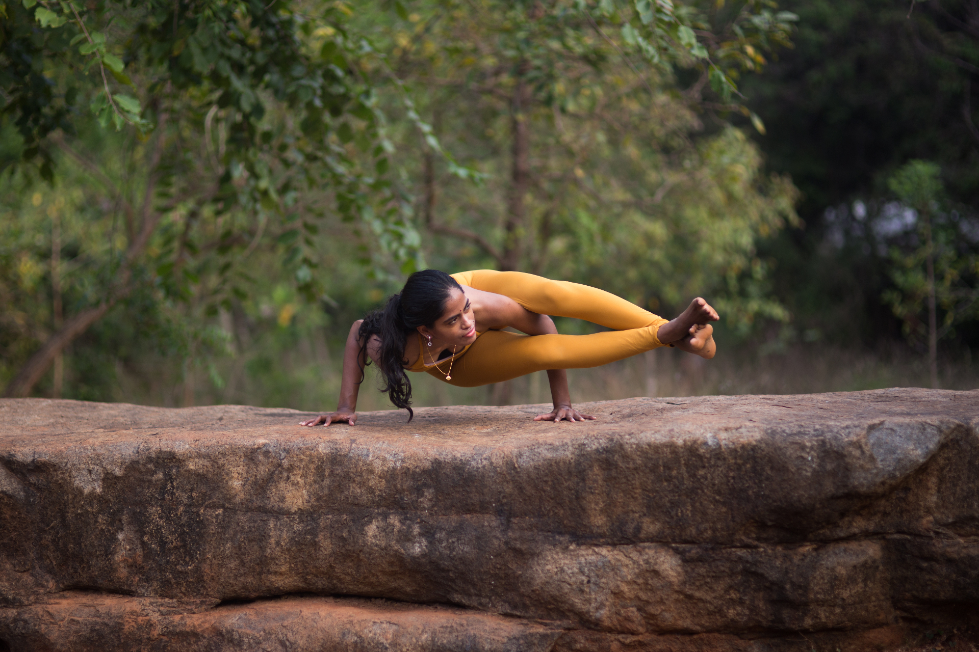 Sneha in an arm balance yoga pose outdoors